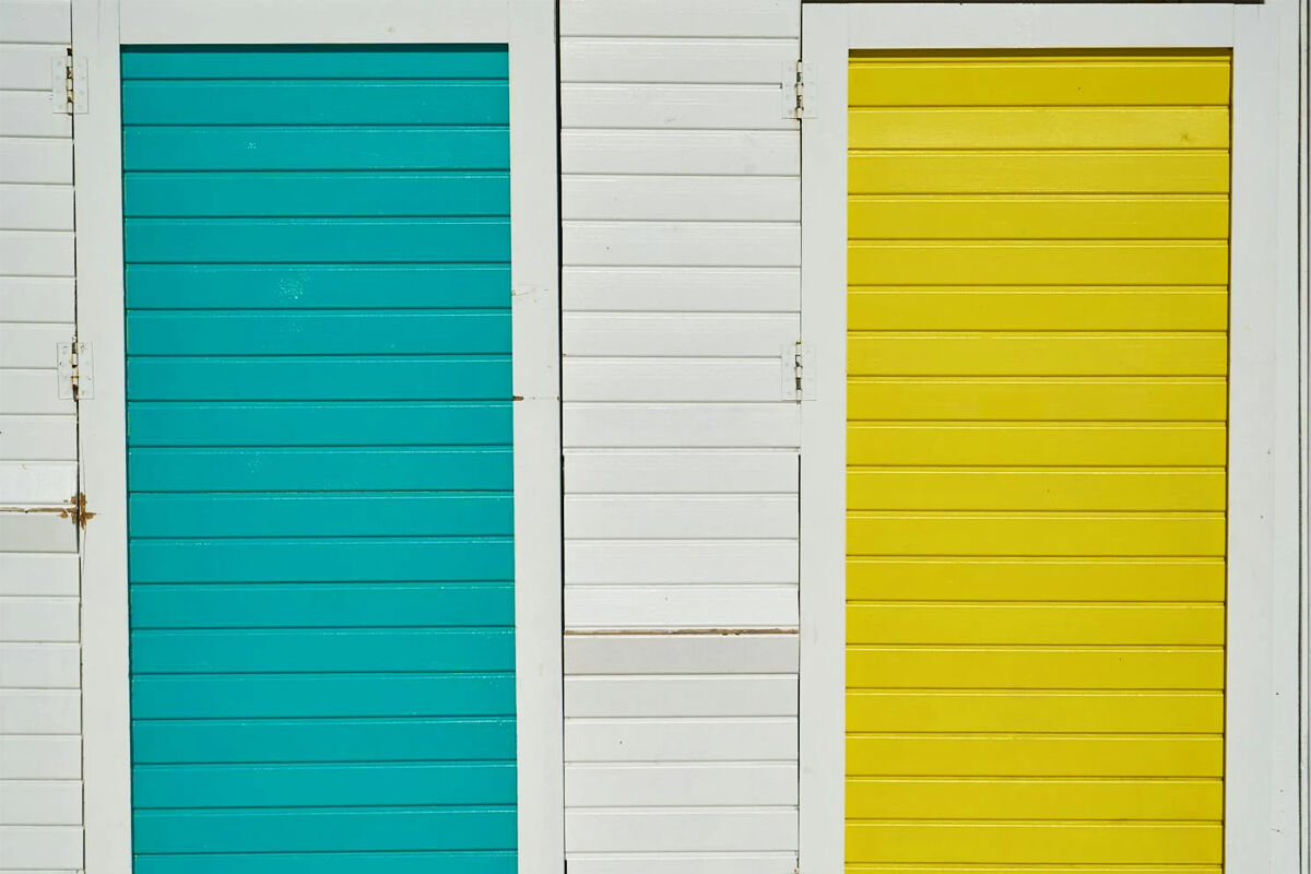 Bright turquoise and yellow wooden doors on white wall